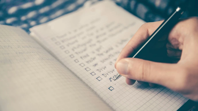 person writing bucket list on book